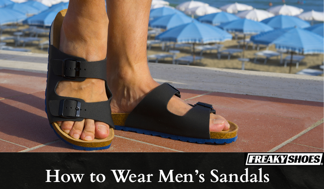 Freaky Shoes black strap sandals with blue sole, worn on beachside tiles near umbrellas
