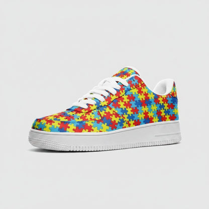 Freaky Shoes® low-top leather sneakers featuring a colorful autism puzzle piece print and white rubber outsole.
