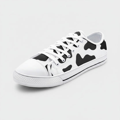 Freaky Shoes® low-top canvas sneakers featuring a black and white cow print pattern with white laces and rubber toe cap.