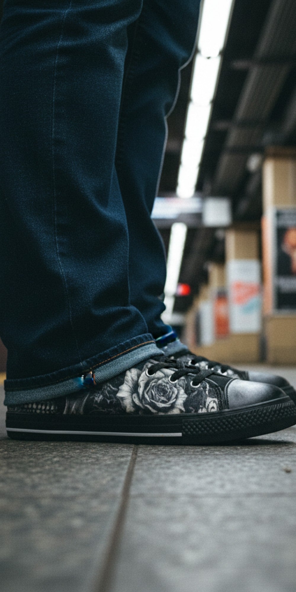 Freaky Shoes® gothic high top canvas sneakers featuring a black and white skull and rose print on a subway platform.
