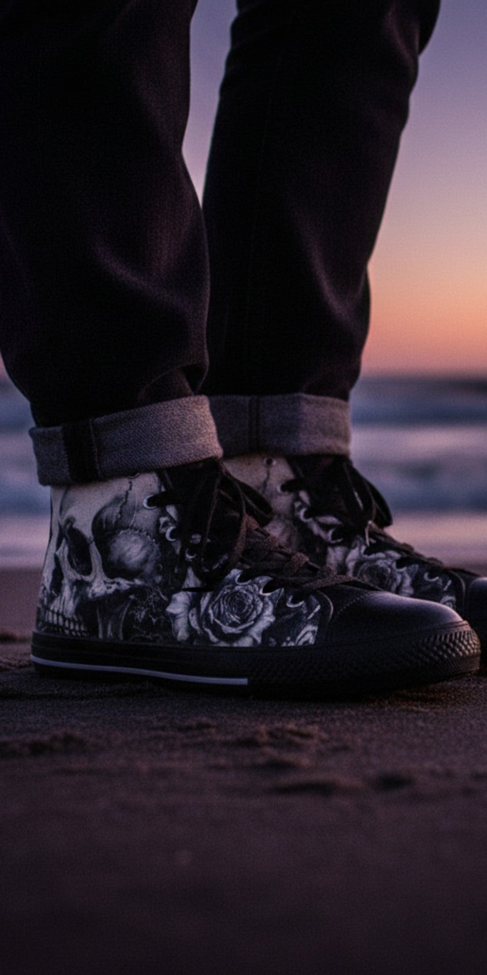 Freaky Shoes® men's high top canvas sneakers with black and white skull and rose art, worn on a beach at sunset.