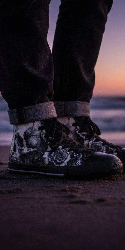 Freaky Shoes® men's high top canvas sneakers with black and white skull and rose art, worn on a beach at sunset.