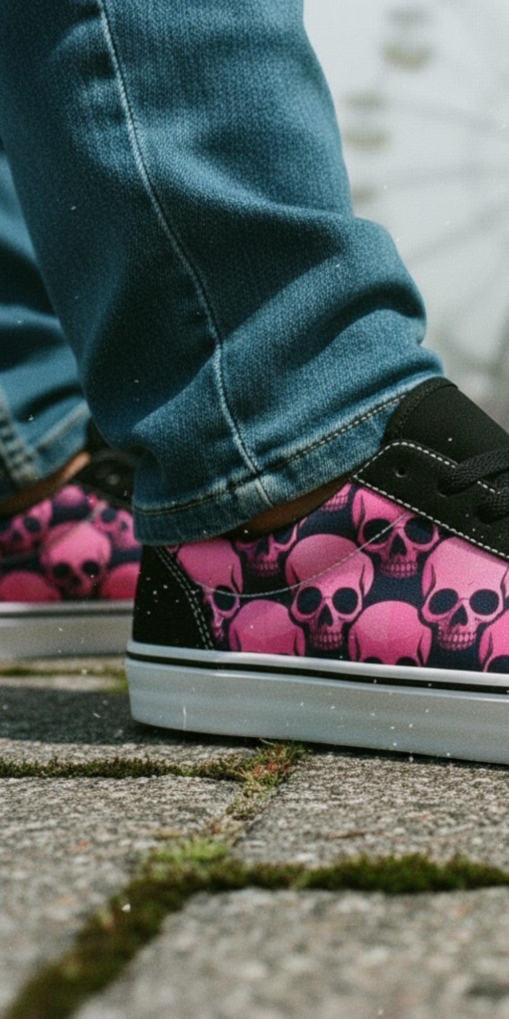 Freaky Shoes® women's low top skate sneakers featuring a pink and black skull comic print on a paved boardwalk.